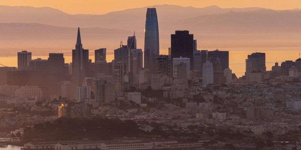 A vertical shot of city buildings in the distance near the sea